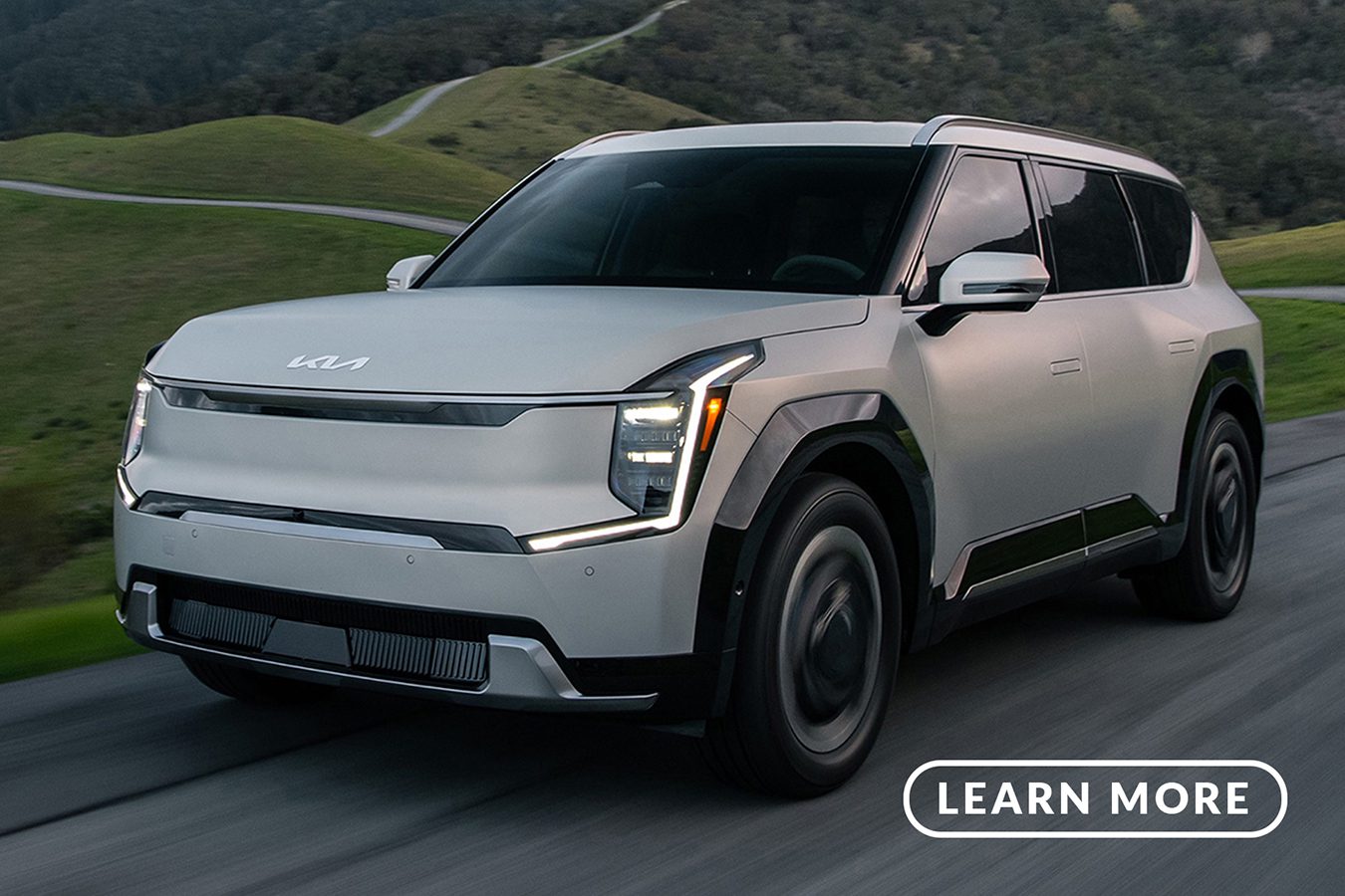 The Kia electric suv is driving down a mountain road.
