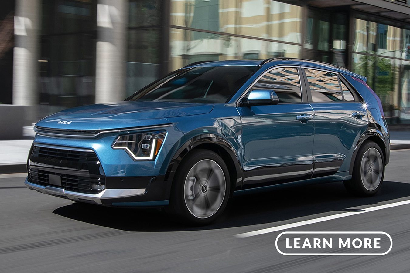 A blue 2020 Kia driving down a city street.