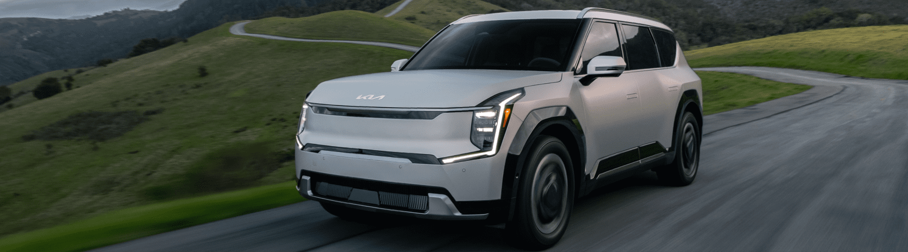 A white suv driving down a mountain road.