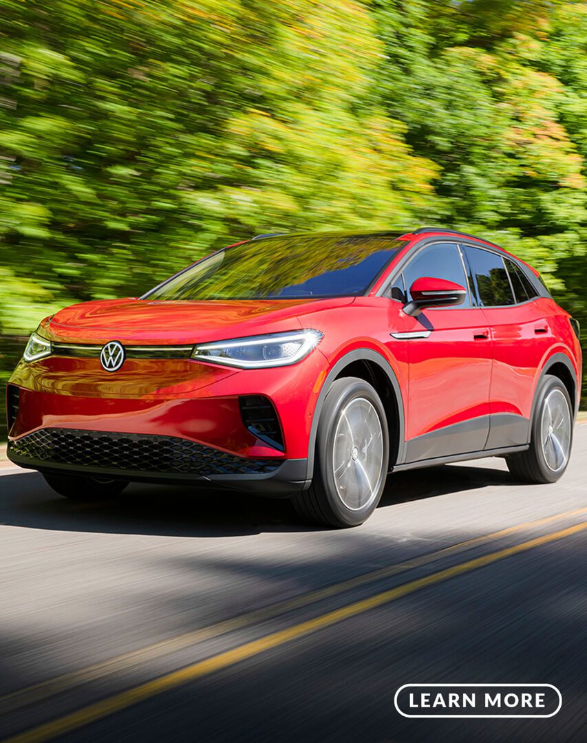 A red volkswagen e - tron driving down a road.