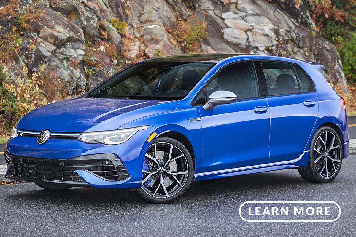 A blue volkswagen golf gti parked in front of a mountain.